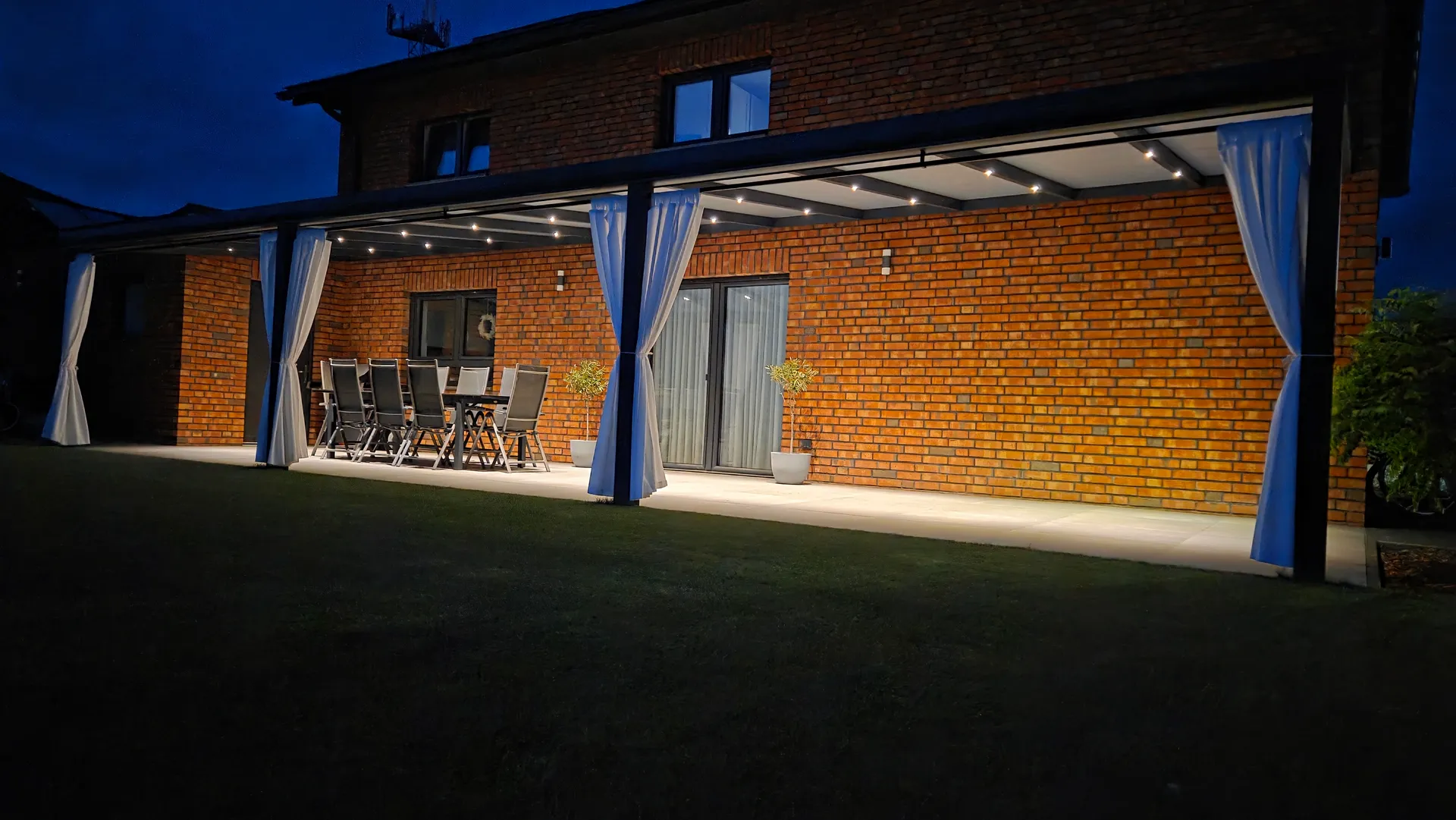 Überdachte Terrasse bei Nacht mit LED-Spots im Dachprofil, Rühen