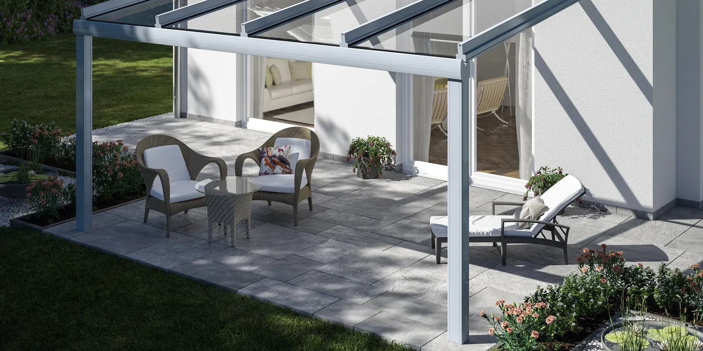 Weißes Glasdach über einer Terrasse mit Sitzgruppe an einem hellen Haus